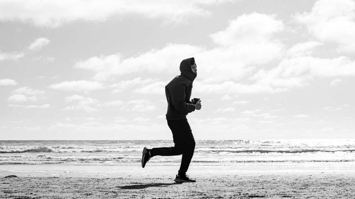 Silhouette of a jogger running along La Lucila del Mar beach, captured in monochrome.